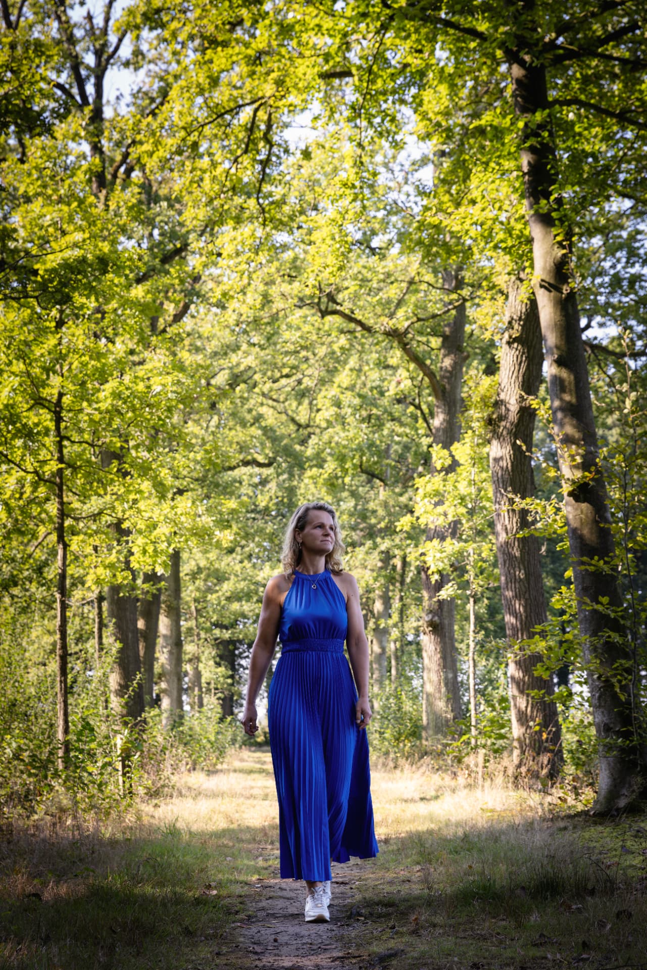 Esther van Krieken in een blauwe jurk op een bospad